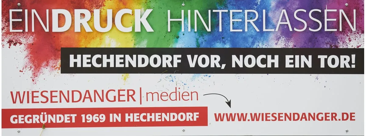 Bunte Bandenwerbung von Wiesendanger Medien mit dem Ruf „Hechendorf vor, noch ein Tor!“